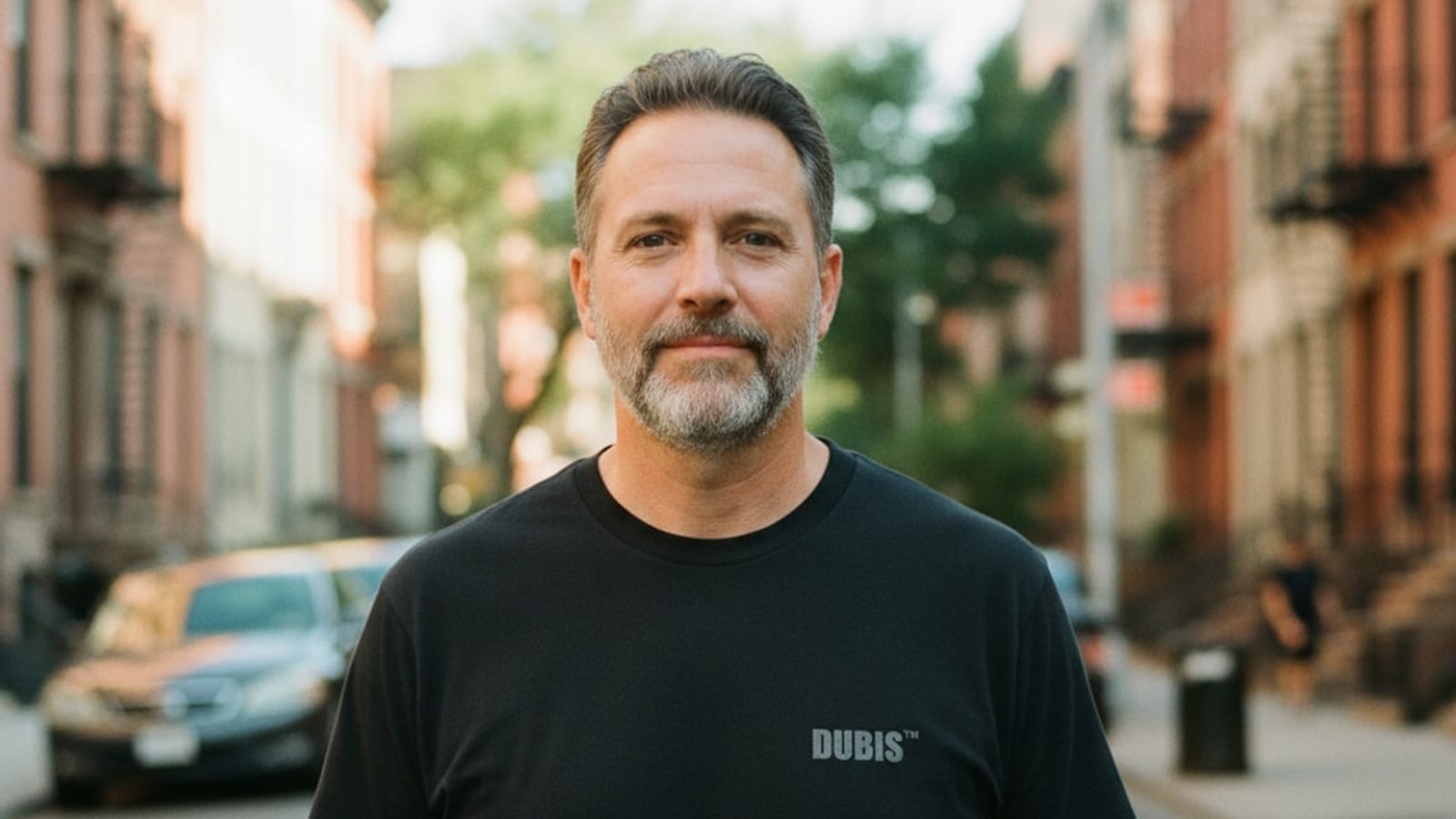 A real man in a black DUBIS t-shirt on a city street — fashion built for the body you actually live in